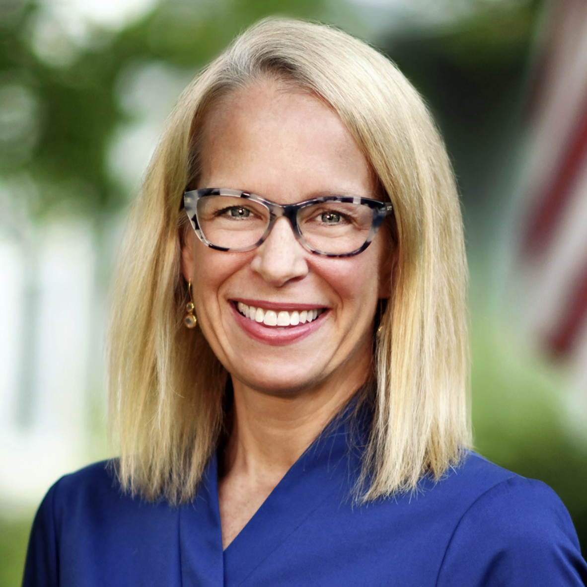 Portrait of Kelly Morrison, a white woman with shoulder-length blonde hair and glasses.