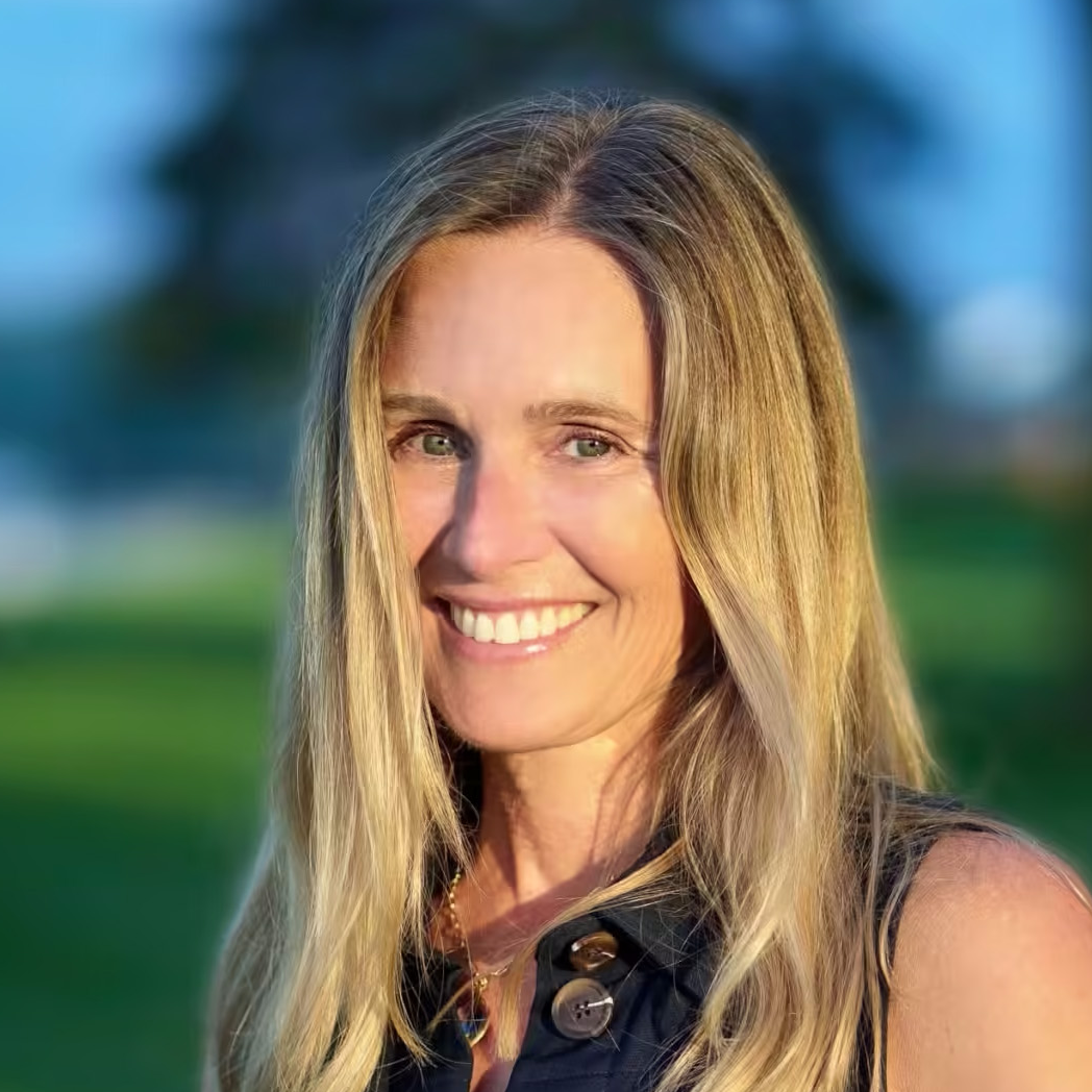 Portrait of Tracey Breazeale, a white woman with long blonde hair outside at golden hour.