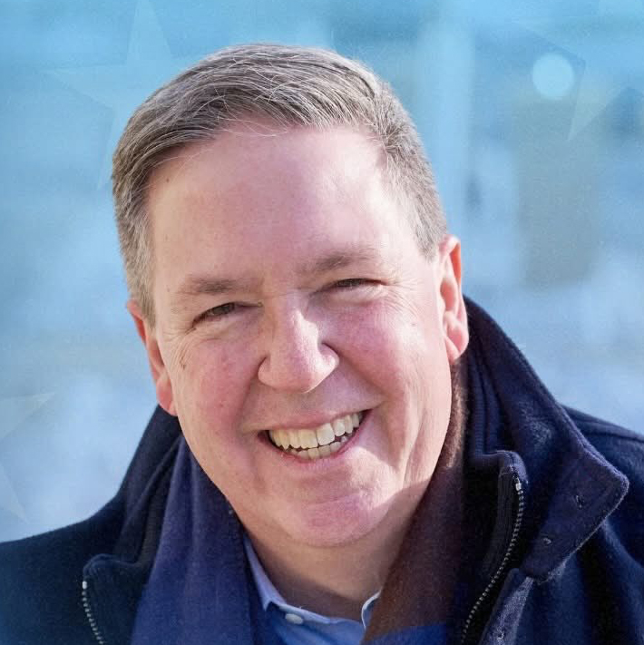 Portrait of Doug Chapin, a white middle-aged man with short grey hair, wearing a winter coat and scarf.